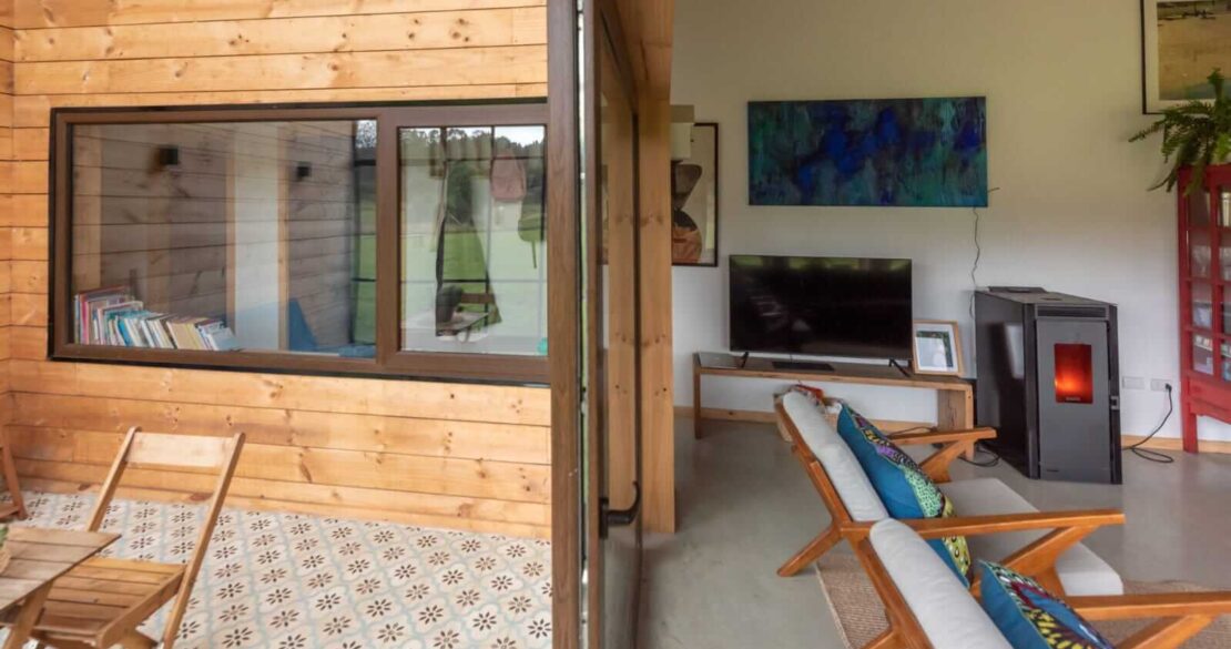 Interior de casa moderna en el sur de Chile con estufa a pellet, mobiliario de madera y ventanales hacia la naturaleza