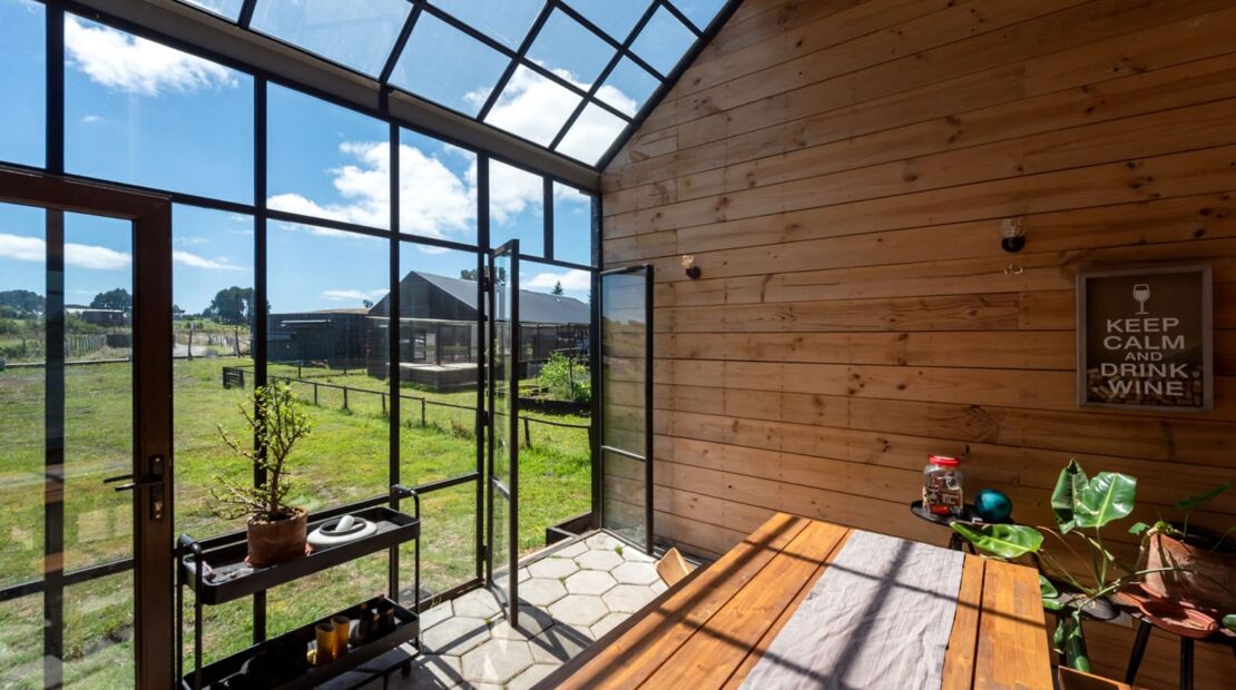 Galería acristalada orientada al sol en casa sustentable diseñada por Estudio Nalca en el sur de Chile.