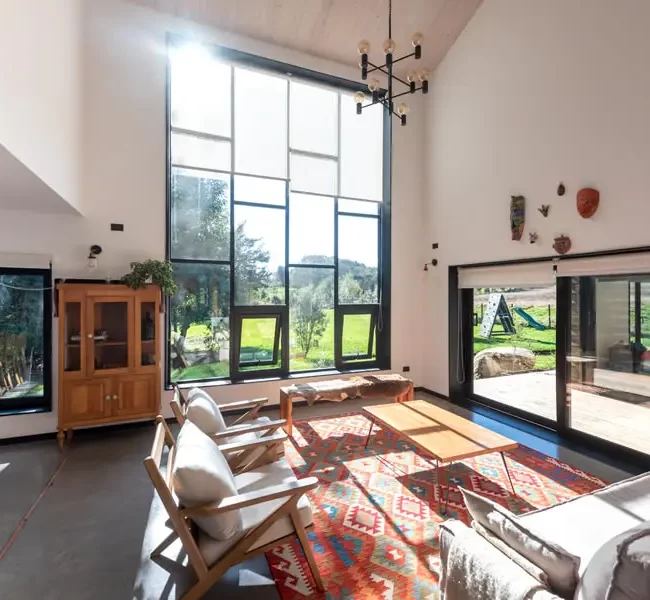 Salón con grandes ventanales (TVH) que aseguran confort térmico y eficiencia. Interior cálido con diseño funcional.