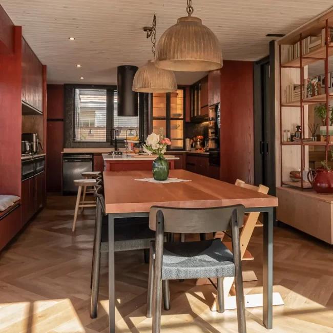 Cocina moderna integrada al comedor con isla central de madera, diseño funcional para ampliar espacios en casas familiares.