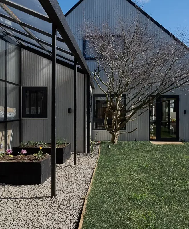 Fachada posterior de casa remodelada en Puerto Varas con revestimiento de zinc y ampliación vidriada, diseño de arquitecto local Estudio Nalca.