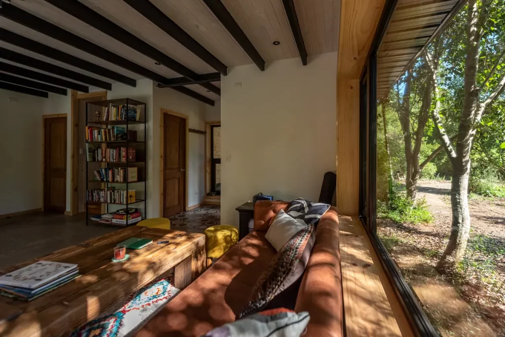 Living de madera con sol directo entrando por ventanal de alta eficiencia.