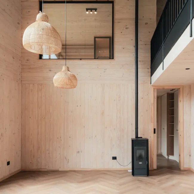 Estar interior de Casa DLM con revestimiento de madera y estufa en Frutillar