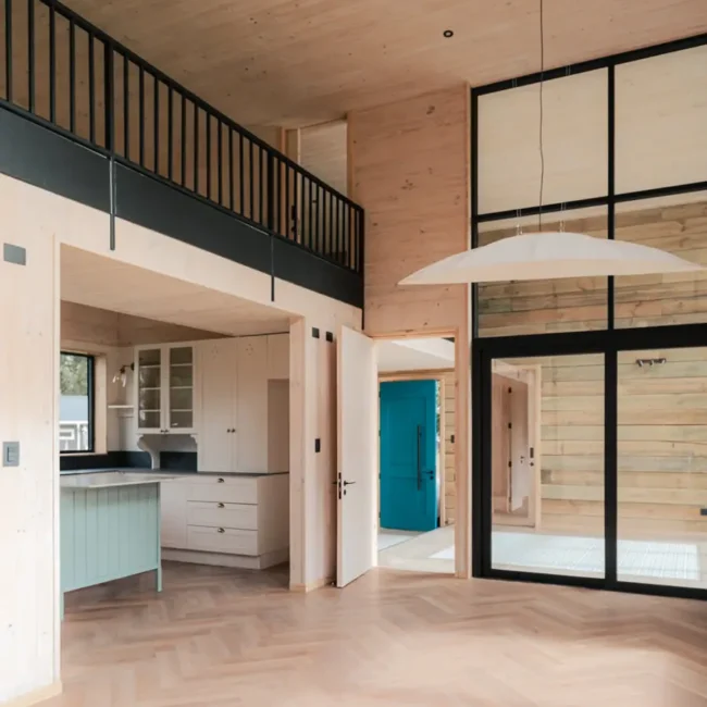Living y cocina de Casa DLM con doble altura y estructura en madera en Frutillar