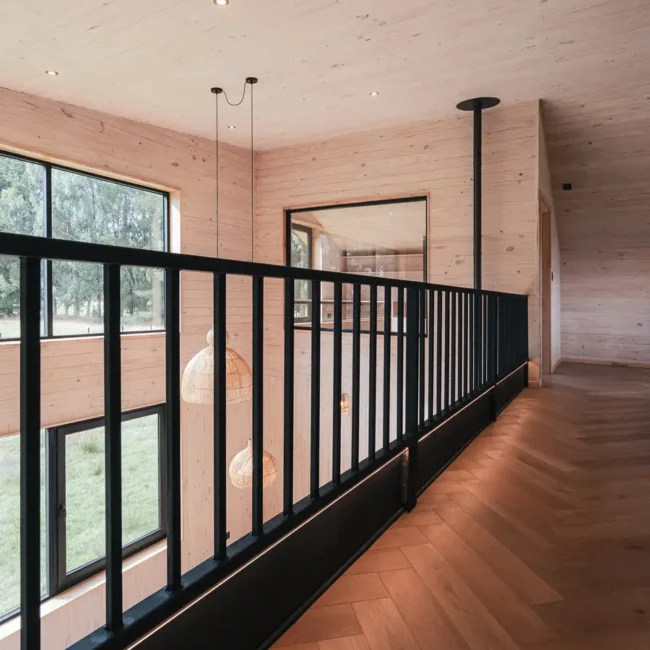 Pasarela interior de segundo nivel en madera de Casa DLM, vivienda diseñada por Estudio Nalca